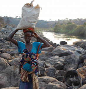 A woman in Angola carries water gathered from the river for washing clothes and bathing her child. Access to clean water is a luxury in rural Angola and many people, like this woman, walk more than 8 kilometres, with their clothing and food on their heads and their babies on their backs. © 2009 Stephanie VandenBerg, Courtesy of Photoshare